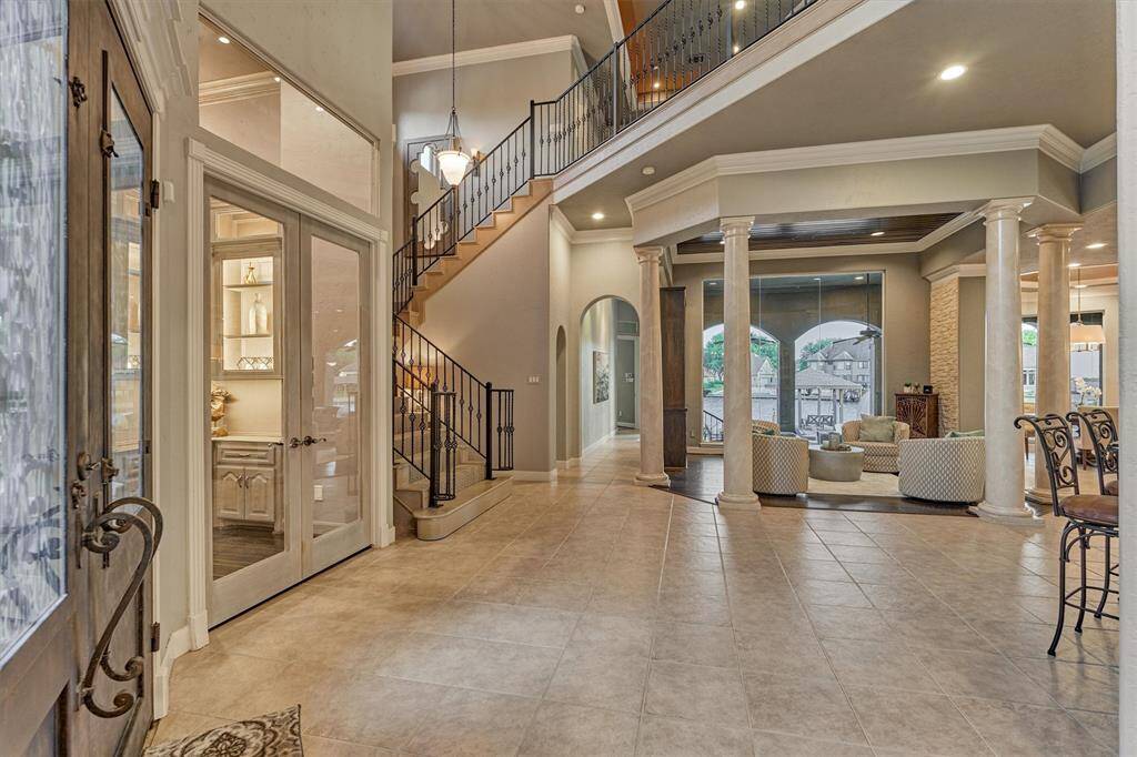 Double doors open to a grand two-story foyer, leading to a sophisticated sitting room and a private office to the left. Featuring crown molding, custom trim, and refined architectural details throughout, this home exudes timeless elegance and thoughtful design.