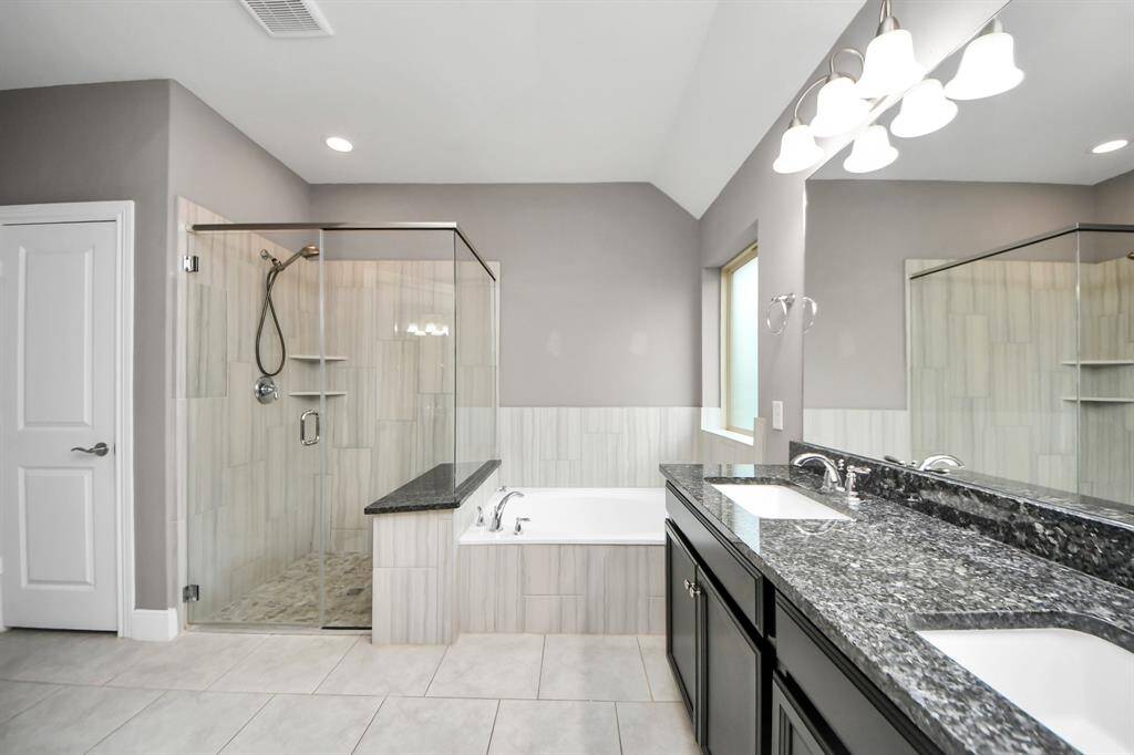 The luxurious en-suite bathroom offers a spa-like retreat, complete with a soaking tub, a separate shower, and a granite vanity with dual sinks.