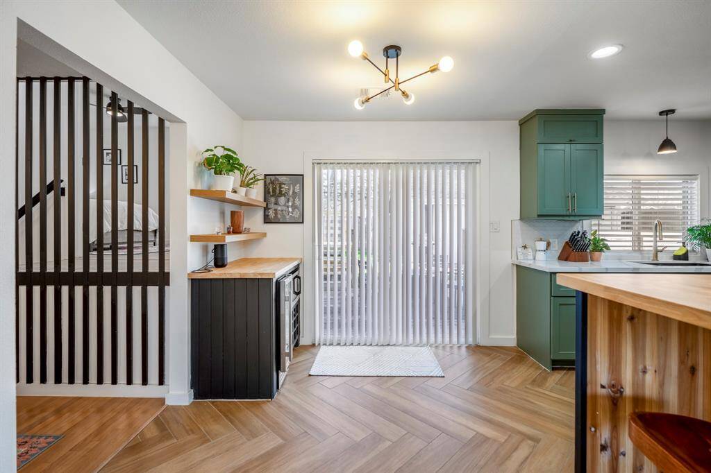 Incredible herringbone flooring in your dining and kitchen area. Built-in bar to the left of this picture with a beverage fridge and microwave. This space would be perfect for a small breakfast table.