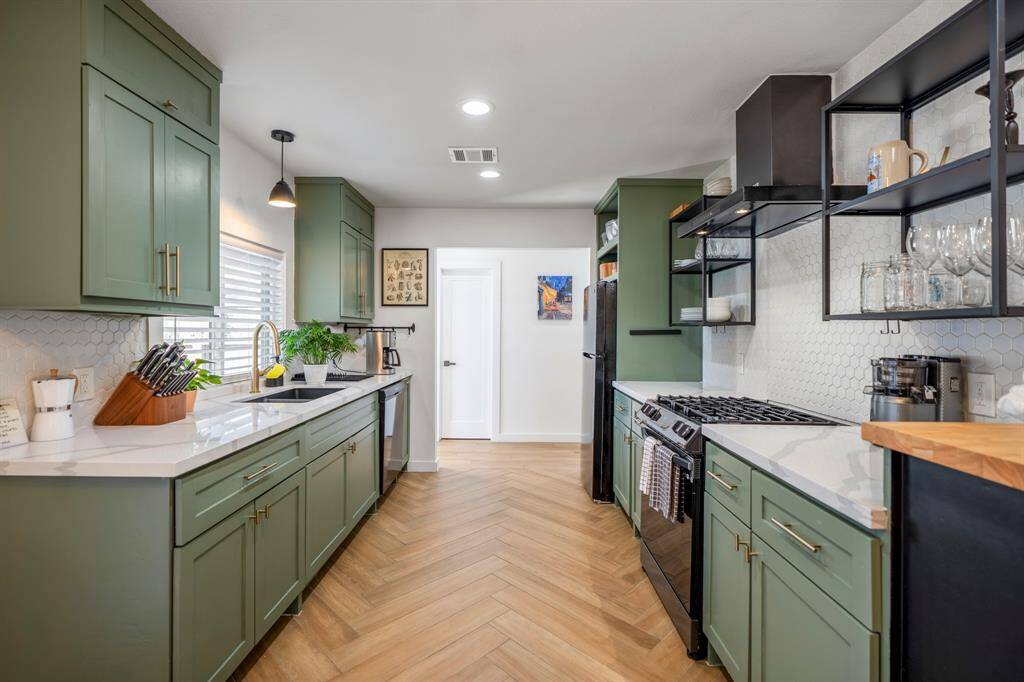 Quartz counters and gas stove that would impress any chef. Closed door in the distance is the powder bath and also a door that leads to the walkway to the garage.