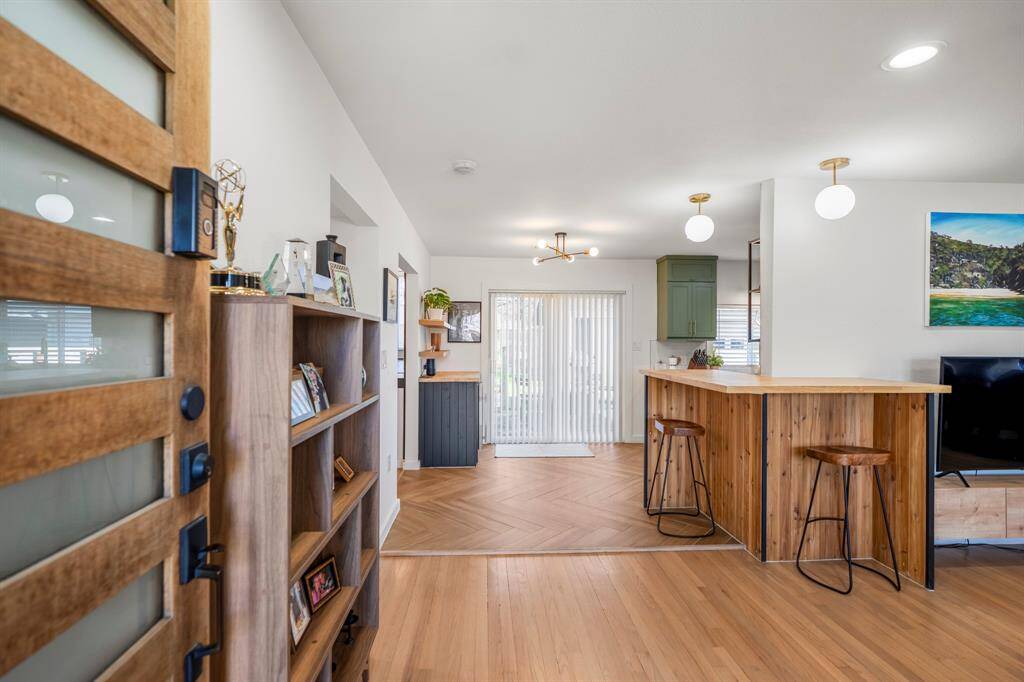 A modern front door welcomes you inside this gorgeous home with hardwoods throughout. Notice bar seating and designer pendant lighting in this open space.