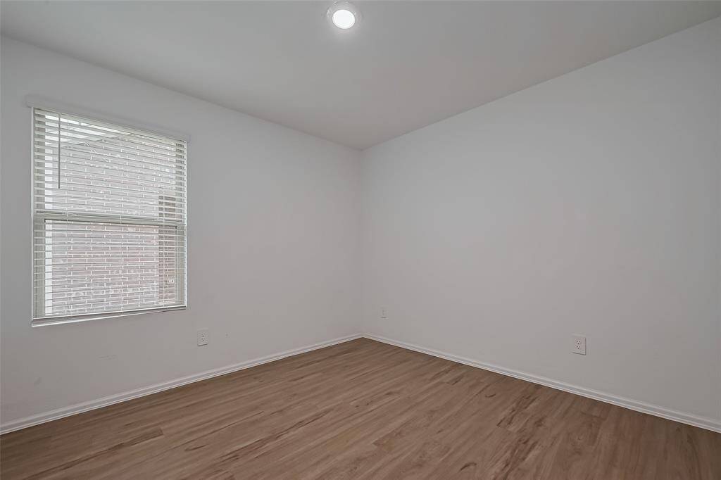 Recessed lighting and a generous window keep this bedroom well-lit at any hour. The neutral color palette makes it easy to personalize, while the layout provides room for both rest and function.