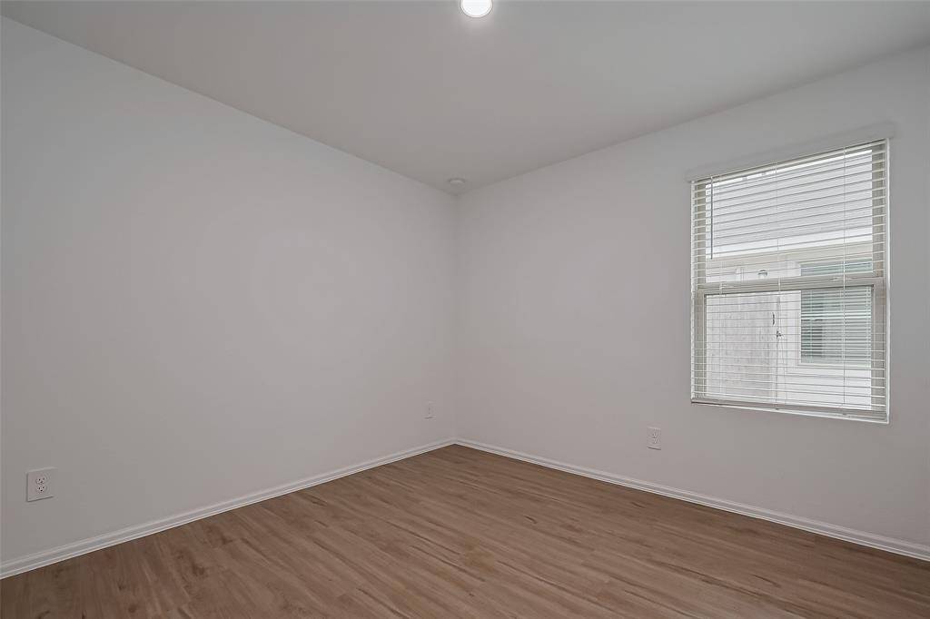 This adaptable space offers endless possibilities—whether used as a bedroom, home office, or hobby room. The expansive window frames outdoor views, while the crisp walls and rich flooring create a modern, cohesive look.