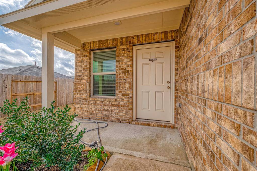 The covered front porch provides a sheltered entryway, blending seamlessly with the warm brick exterior. A stylish front door complements the home’s design, creating an inviting first impression. This thoughtful detail enhances both aesthetics and practicality, offering a shaded spot to pause before stepping inside.
