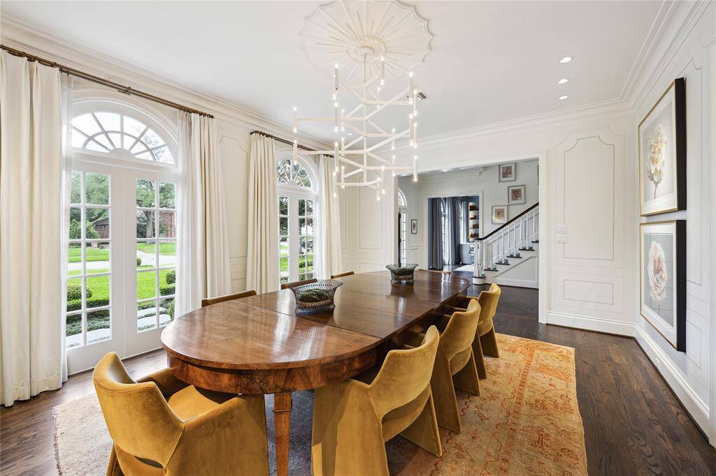 Elegant and inviting, the Dining Room showcases floor-to-ceiling arched windows, white silk faille drapery, Antique French sconces from Joyce Horn Antiques, and a gas fireplace.