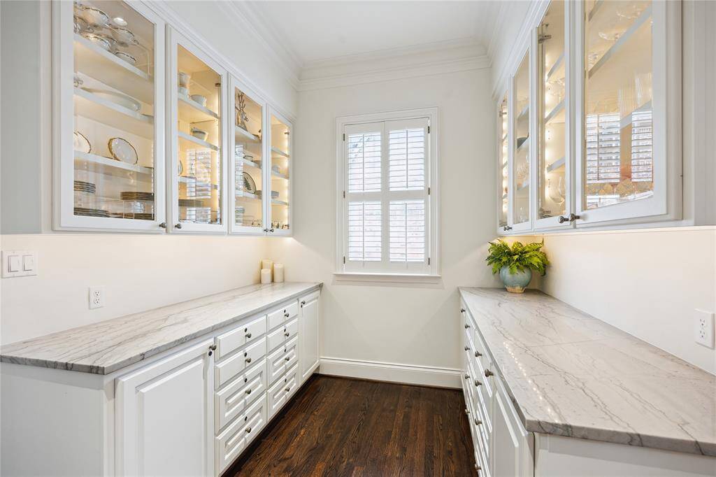 A bright Butler’s Pantry features elegant glass-front cabinetry, quartzite countertops, and ample storage.