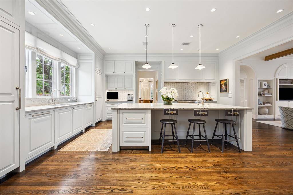 This elegant Kitchen features a spacious quartzite-topped island with bar seating, Ann Sacks mosaic backsplash and Hector Finch ceramic pendant lighting.