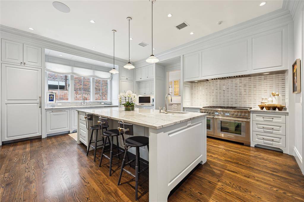This bright Kitchen exhibits walls paneled and painted in “Borrowed Light” by Farrow and Ball and includes paneled appliances
