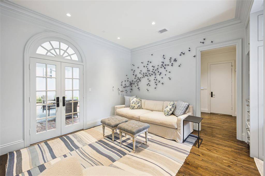 This serene Sitting Area features French doors that lead to a charming outdoor covered patio. The hallway beyond this room leads to the Utility Room, one of the two downstairs Powder Rooms, and the Garage.