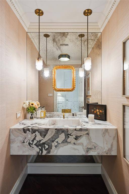 This elegant Powder Room features a custom designed sink by ML Interiors and Dillon Kyle Architects, floor to ceiling antiqued mirror, soft pendant lighting from Allied Maker, and soft pink grass cloth walls.