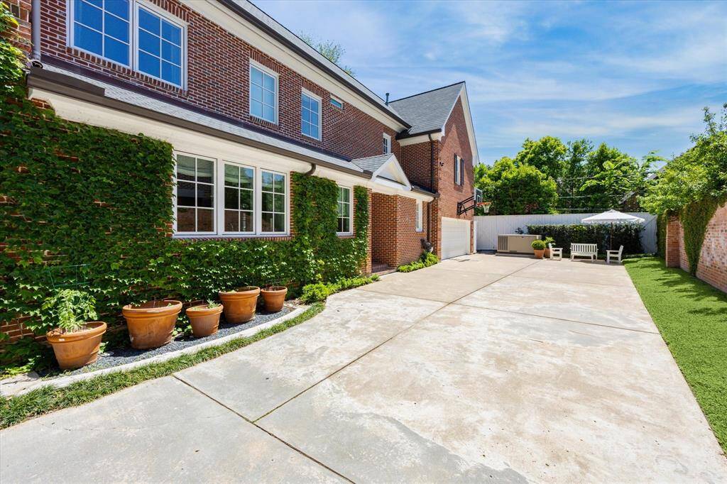 Beautiful vines provide the perfect green addition to your wide driveway.  The whole house generator was an addition during the extensive 2021 renovation.