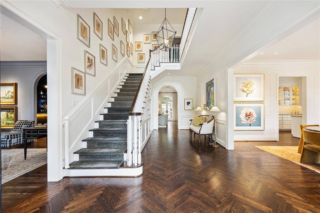 A bright and elegant Entry blends classic charm with modern artistry, featuring oak herringbone floors, high ceilings, and a grand staircase.