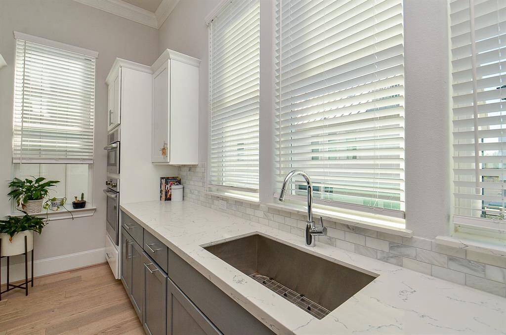 Wall of windows bring in tons of natural light.  The combination of darker and light cabinets adds to the kitchen appeal.  Stainless steel farm sink is an added plus.