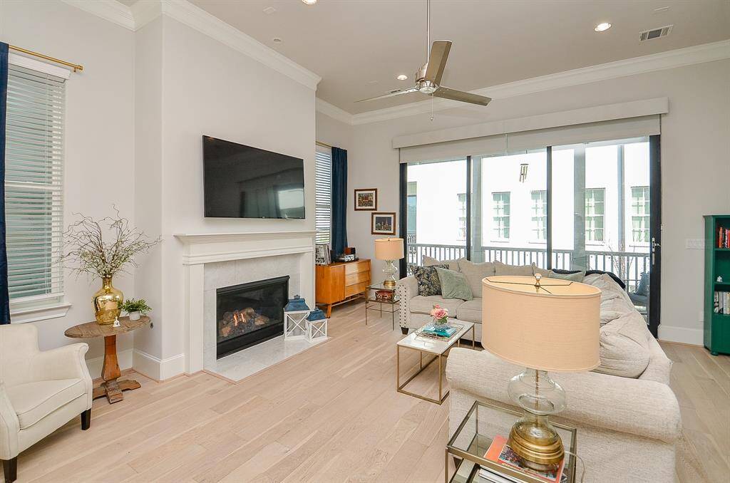 Oversized living area with multiple windows letting in natural light. Tri-paneled sliding glass doors give access to the balcony which overlooks the courtyard. Custom shades and 2" blinds lend privacy to the home.