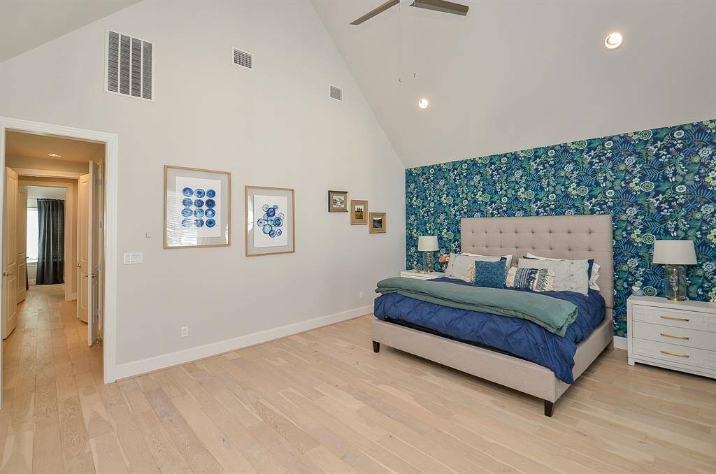High ceilings, light wood flooring, can lights and ceiling fan completes the beautiful primary bedroom.