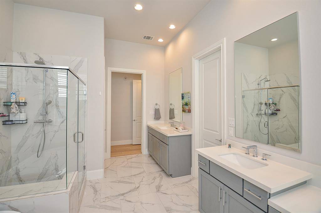 Oversized shower with handheld shower head and shower bench.  Door to right leads to the large primary closet.