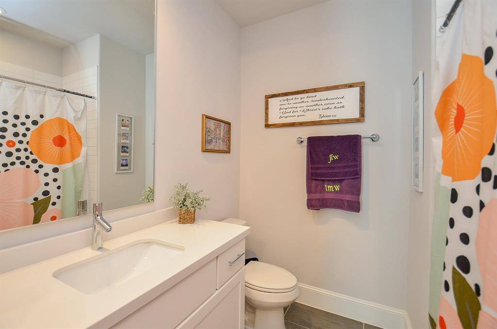 Secondary bathroom with lots of counter space, drawers and cabinet. Wood tile flooring and light-colored walls.