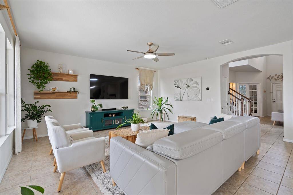 Living room features tile flooring, aceiling fan, and large windows.