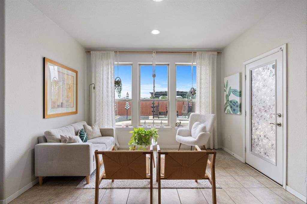 The sitting area off the living room features tile floors, large windows, and recessed lighting.