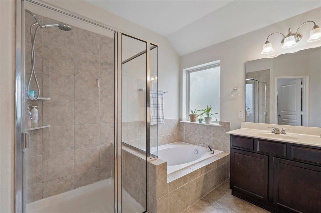 The primary bathroom features tile floors, walk-in shower, separate tub, and frosted window.