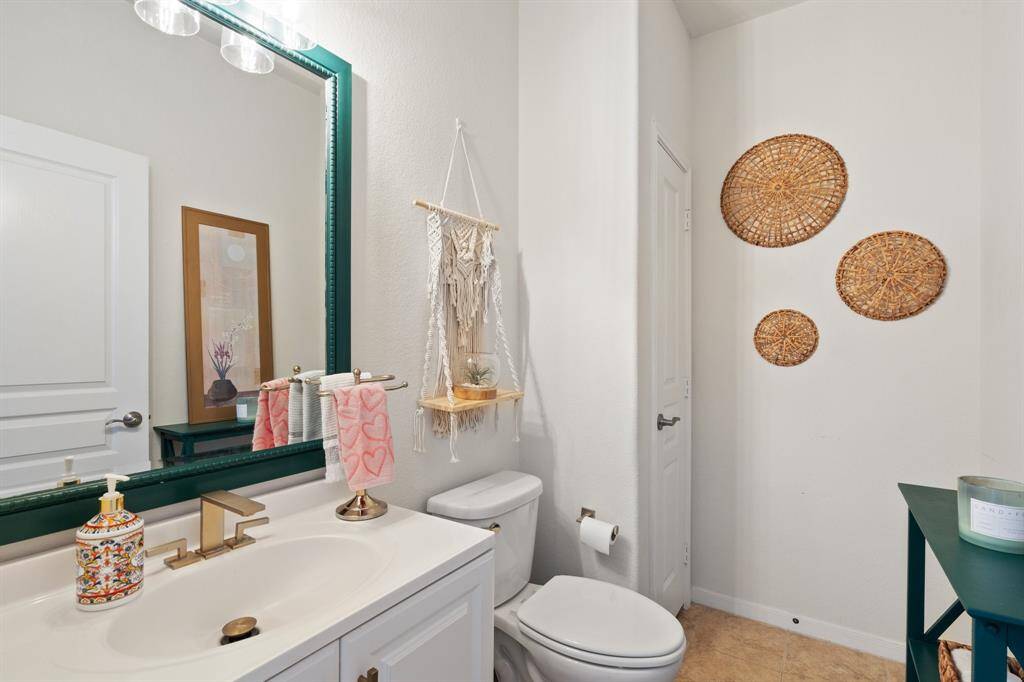 The half bathroom features tile floors and plenty of storage space.