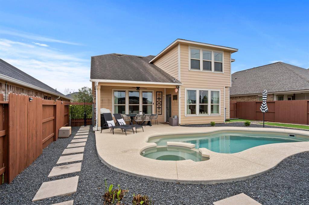The backyard has a paved walkway around the pool.
