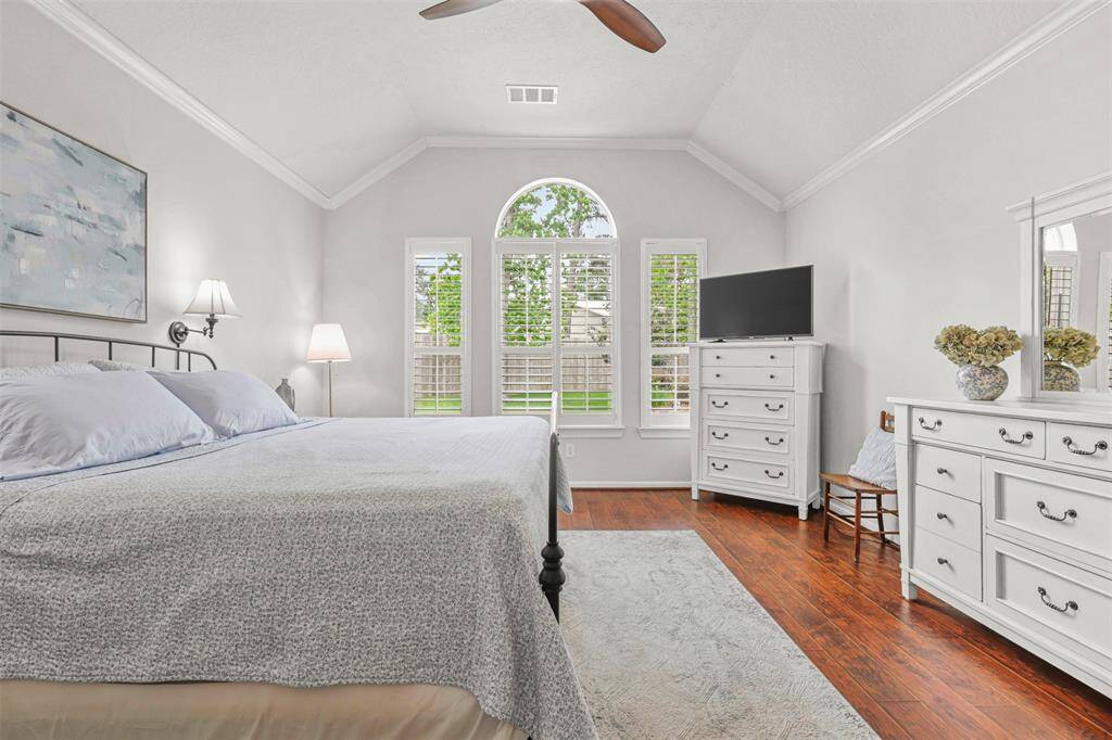 The spacious primary suite with crown moulding, elegant flooring, plantation shutters and updated colors provides views of the backyard oasis.