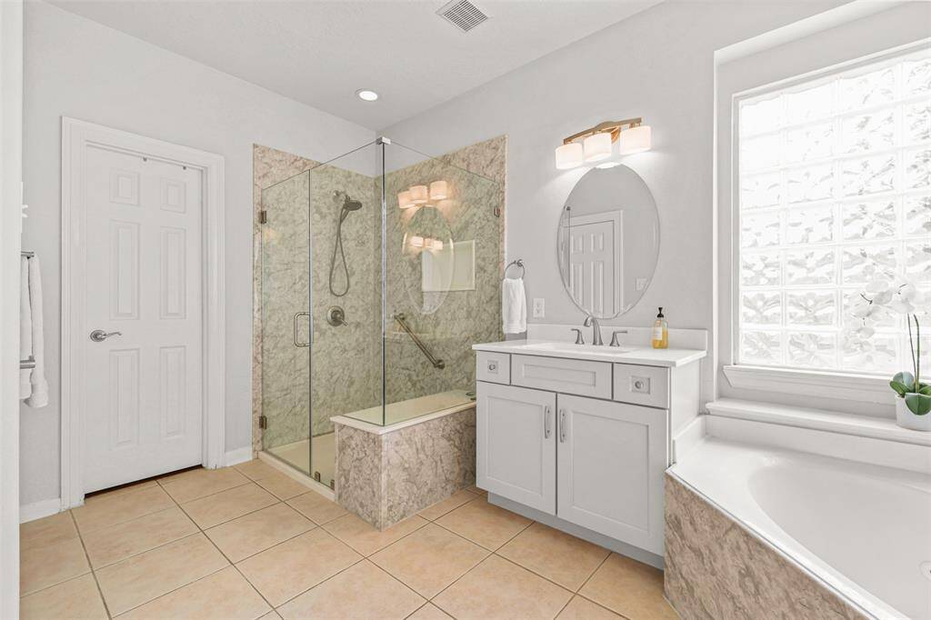 The remodeled primary bathroom boasts sleek, modern finishes and a frameless shower.