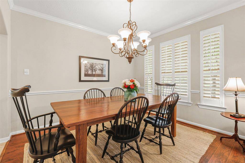 Plantation shutters, crown moulding and wood toned flooring elevate this dining space.
