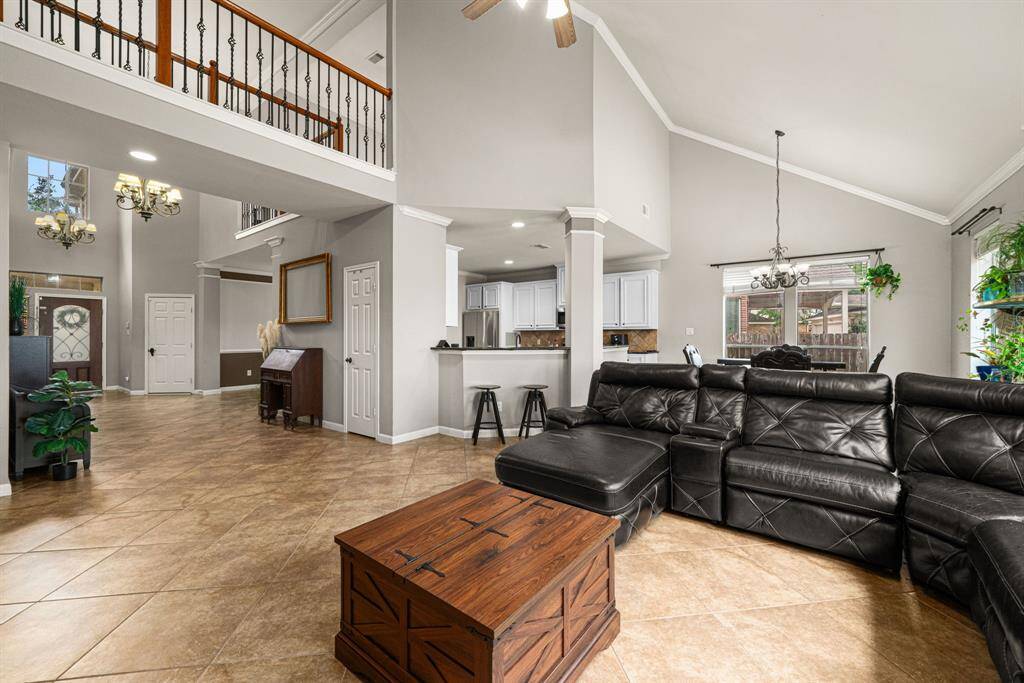 This home welcomes you with an impressive two-story entry that immediately showcases the expansive living room windows, flooding the space with natural light. The seamless open floorplan creates effortless flow between living areas, enhanced by a second-floor balcony that overlooks both the grand entry and living room below. Premium tile flooring unifies the common spaces, offering both elegance and durability.