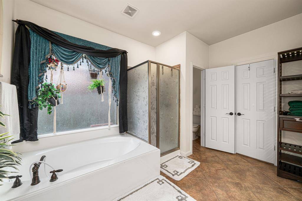 The elegant ensuite bath offers dual vanities, a freestanding soaking tub, and a spacious walk-in shower, while the generously sized walk-in closet completes this private sanctuary.