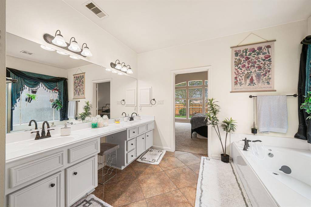 The elegant ensuite bath offers dual sinks and vanities, a freestanding soaking tub, and a spacious walk-in shower, while the generously sized walk-in closet completes this private sanctuary.