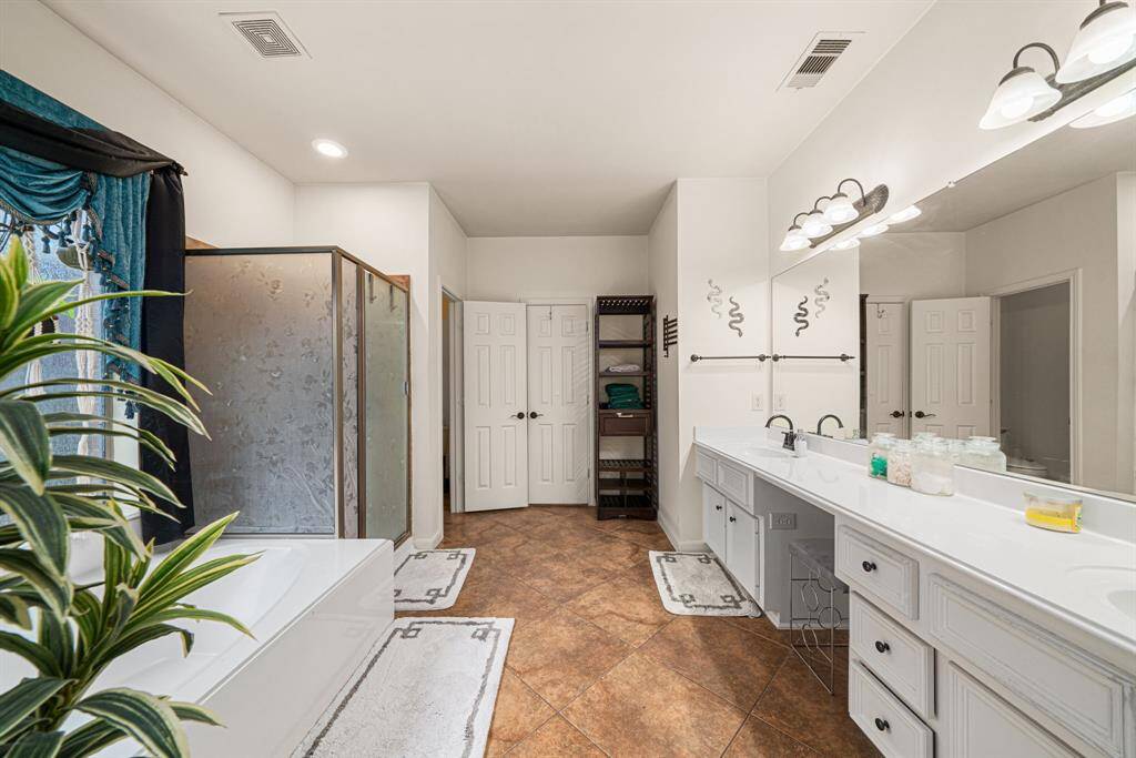 The elegant ensuite bath offers dual sinks and vanities, a freestanding soaking tub, and a spacious walk-in shower, while the generously sized walk-in closet completes this private sanctuary.