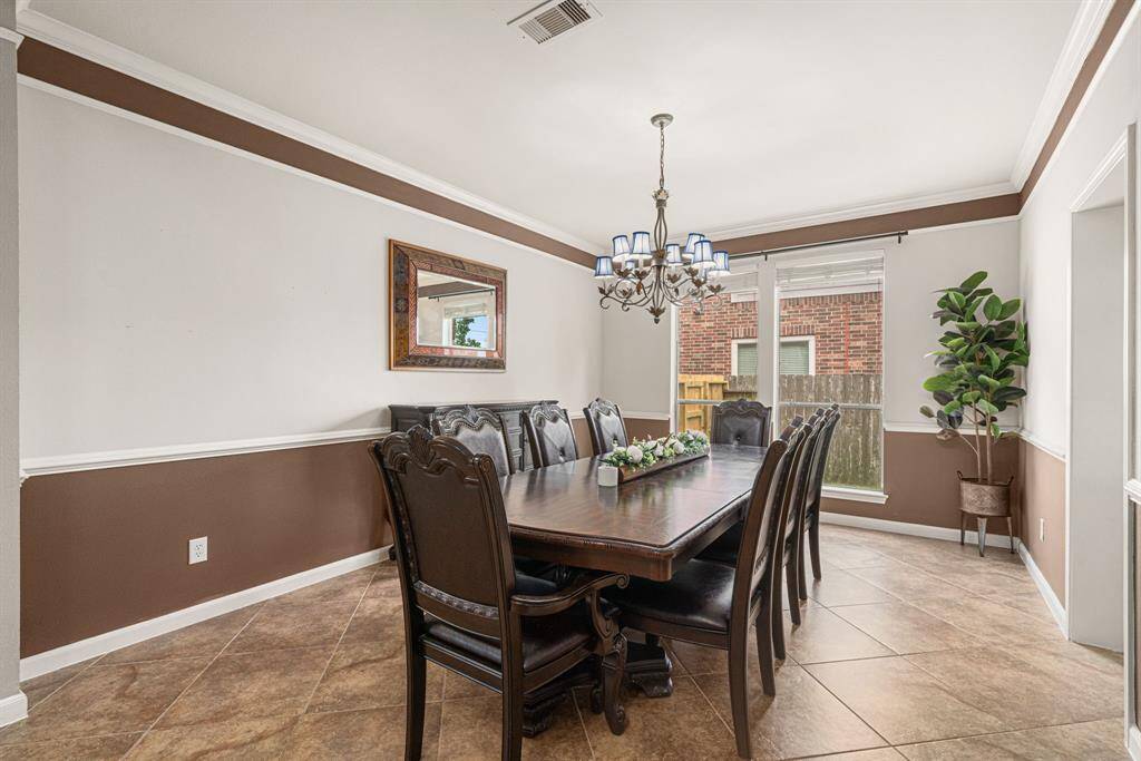 This elegant dining space features direct access to the kitchen for effortless entertaining, enhanced by large windows that flood the room with natural light. The refined aesthetic is completed by easy maintenance tile flooring and graceful crown molding, creating a perfect blend of functionality and timeless style.