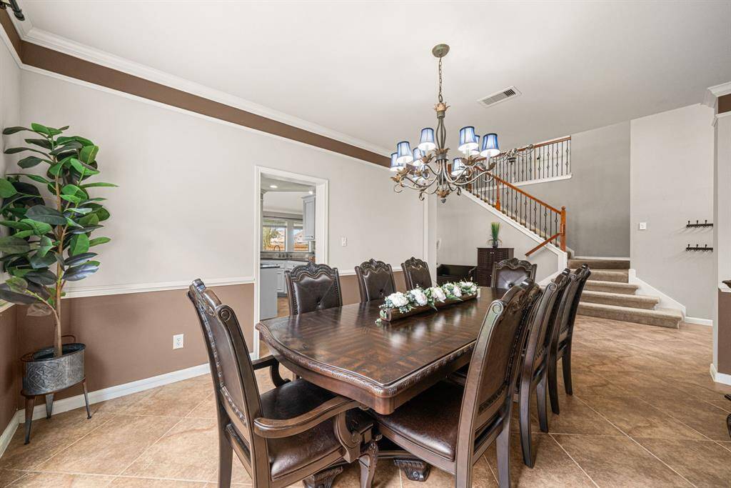 This elegant dining space features direct access to the kitchen for effortless entertaining, enhanced by large windows that flood the room with natural light. The refined aesthetic is completed by easy maintenance tile flooring and graceful crown molding, creating a perfect blend of functionality and timeless style.