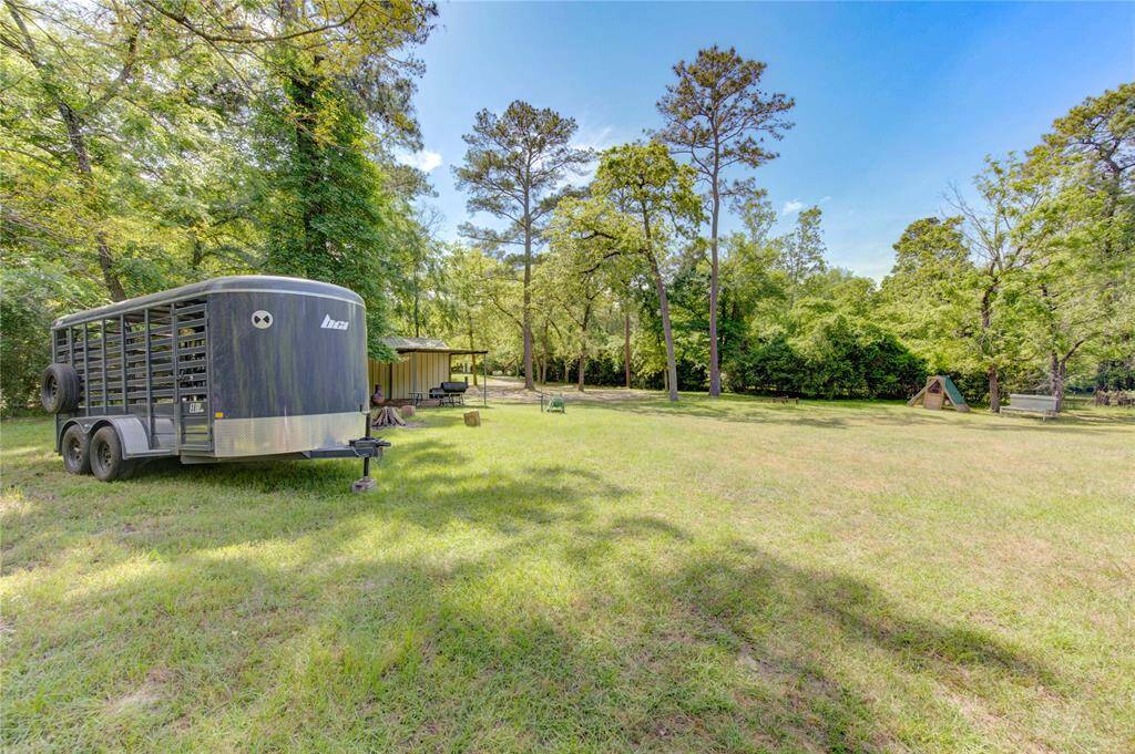 Expansive backyard with lush greenery, mature trees, and a spacious, open lawn. Features a trailer and a small shed, offering ample storage and outdoor possibilities. Ideal for nature lovers seeking tranquility.