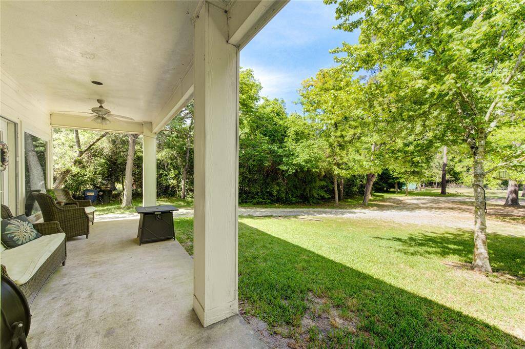 This photo showcases a serene, covered patio with comfortable seating, overlooking a lush, green yard surrounded by trees, providing a peaceful and private outdoor space.