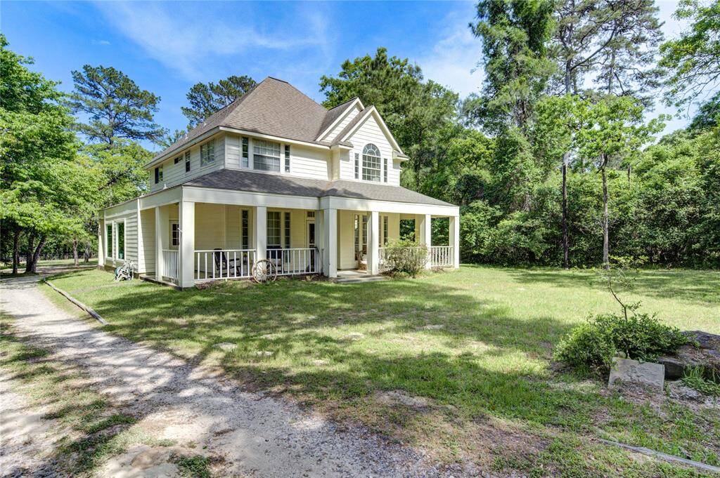 Charming two-story home with a classic front porch, nestled in a lush, wooded area. It features a spacious yard and a serene setting, perfect for enjoying nature.