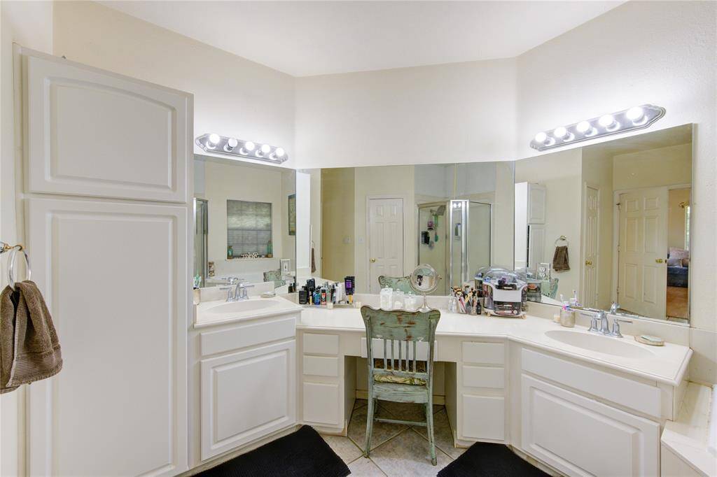 This bathroom features a spacious double vanity with ample counter space, large mirrors, and bright lighting. The cabinetry provides plenty of storage, and the neutral tones create a clean, inviting atmosphere.