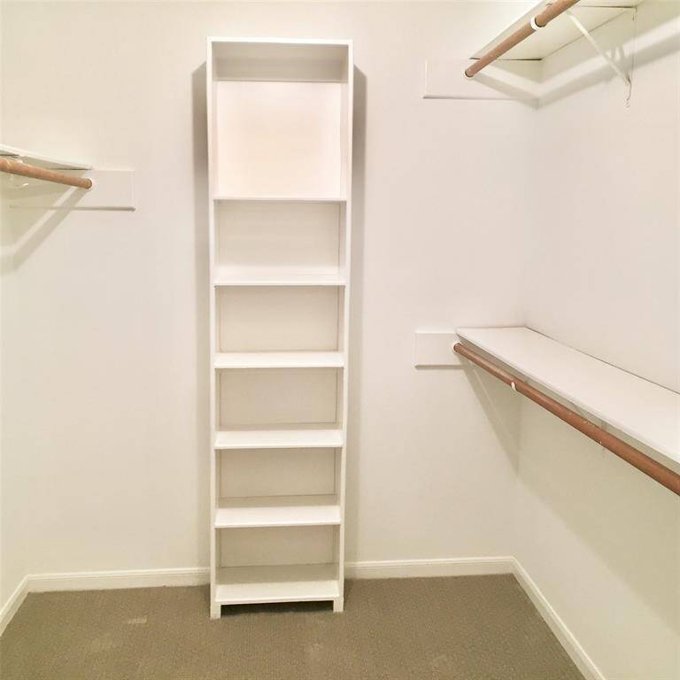 The PRIMARY BEDROOM SUITE  CLOSET has three rods for hanging and 9 Flat shelves.  The floor is carpeted and the closet is well lit.