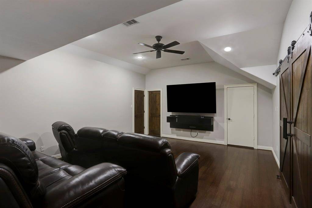 This spacious game room is designed for ultimate relaxation and entertainment, featuring plush recliners and a large, wall-mounted TV for a true theater-like experience. Rustic barn doors lend a stylish, modern-farmhouse vibe, and the neutral color palette makes it easy to customize the space.