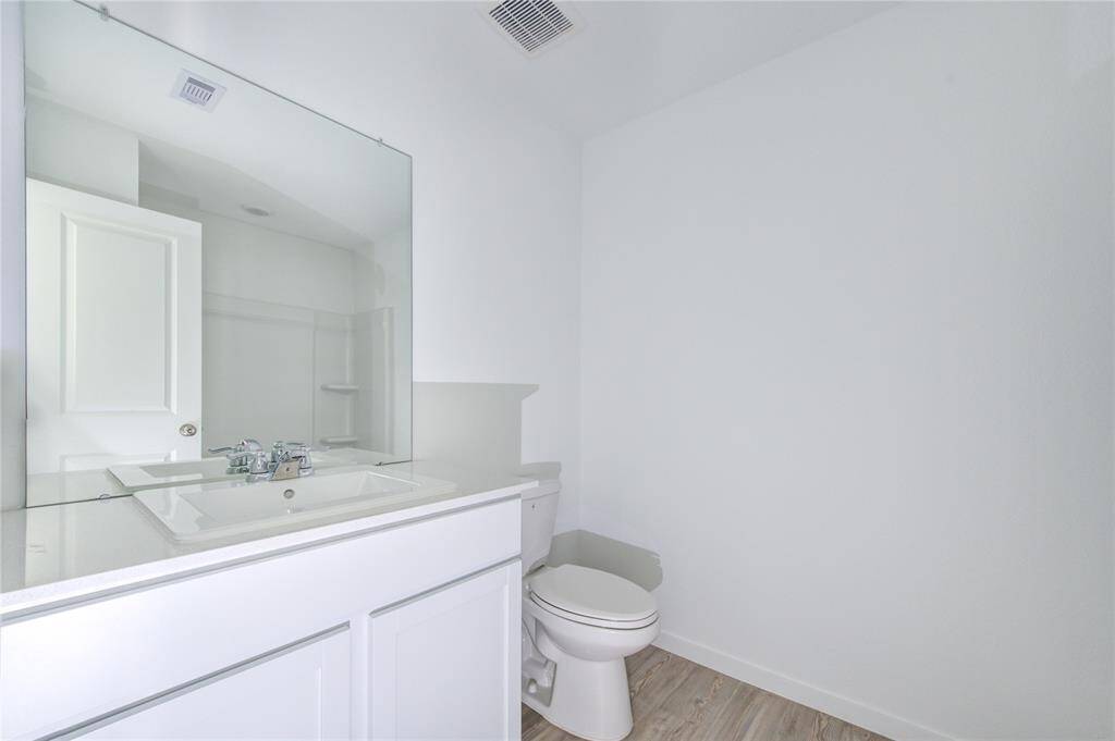 Modern minimalist bathroom with a vanity, large mirror, and toilet