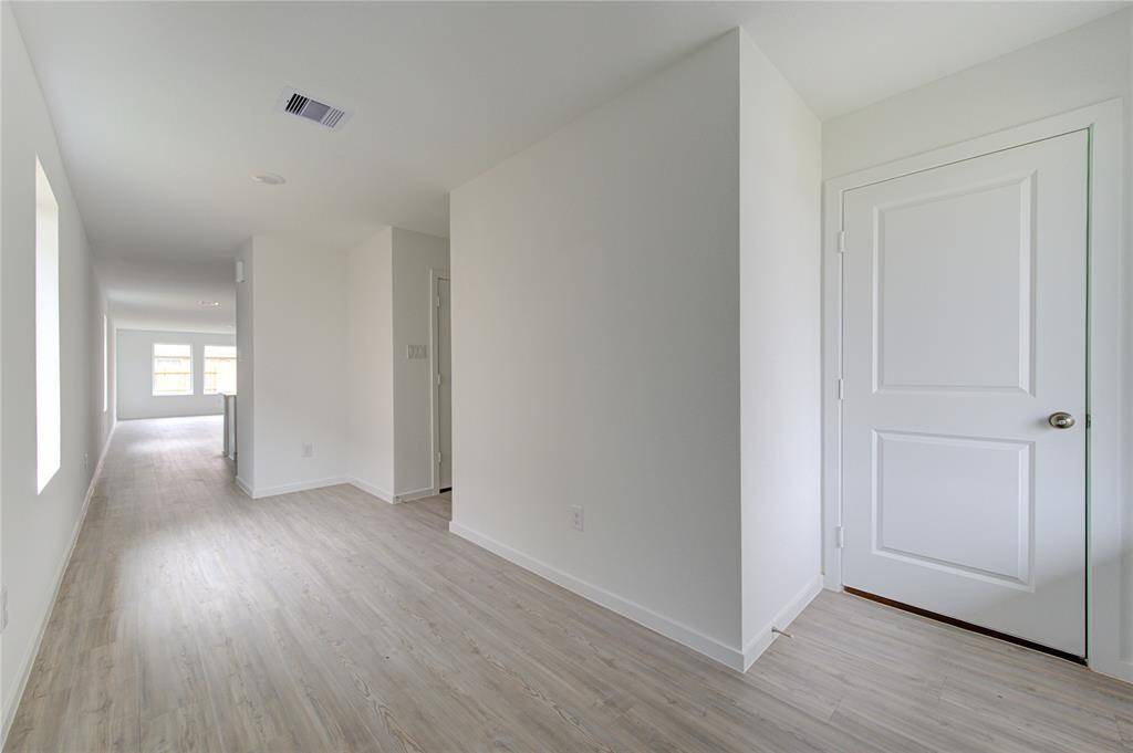 Bright entryway with light wood flooring and multiple doorways