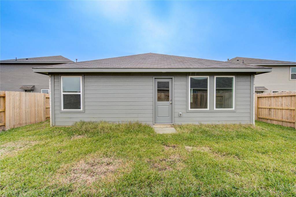 Back view of a single-story gray house with fenced yard