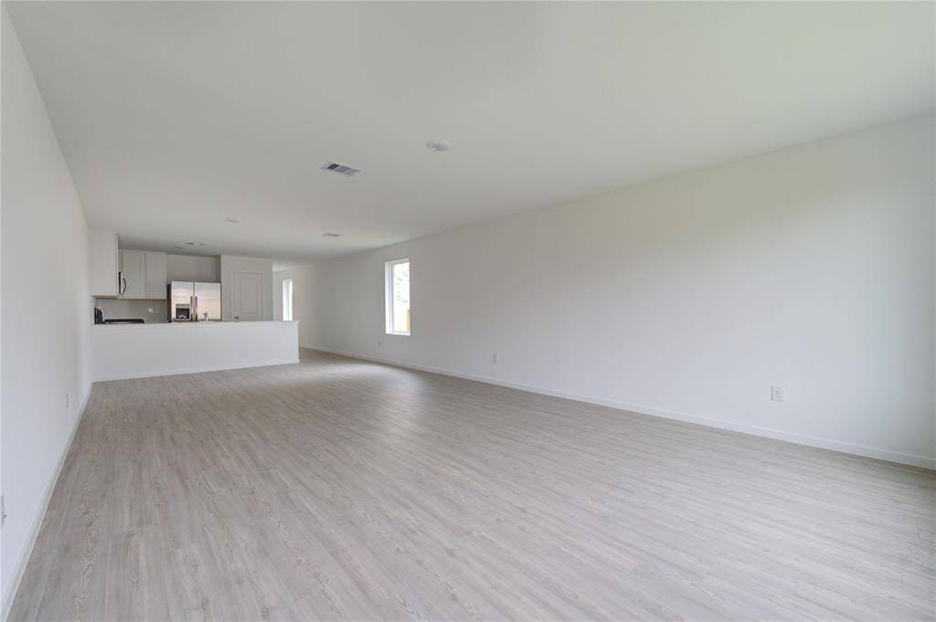 Light wood flooring, hite walls, and a modern kitchen