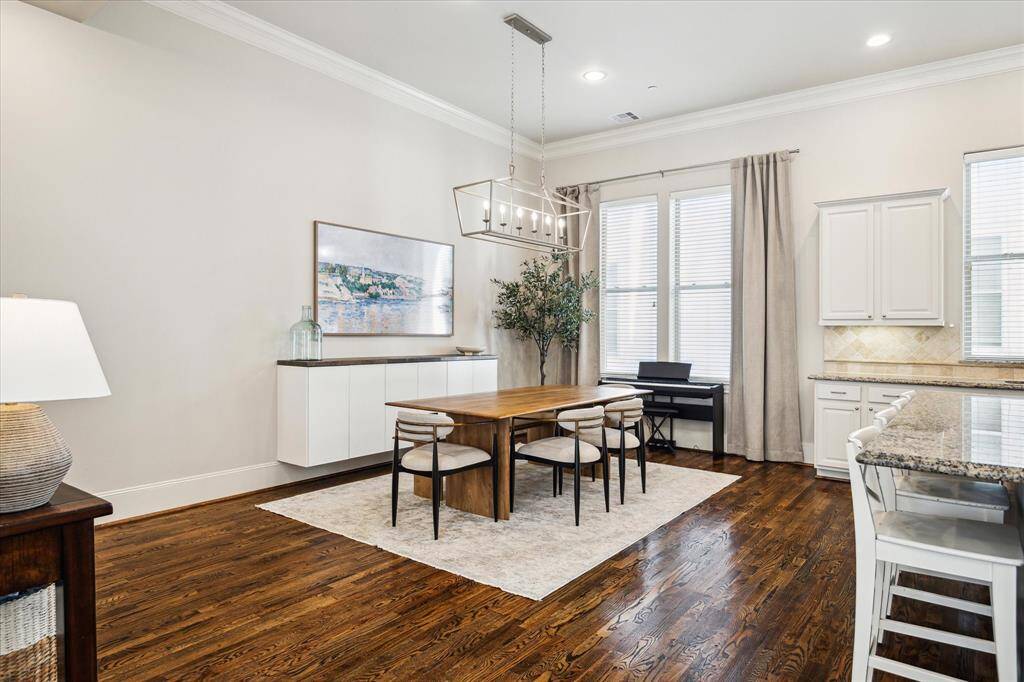 Plan your next dinner party in the windowed dining area featuring wall-mounted cabinetry and an elegant box chandelier.