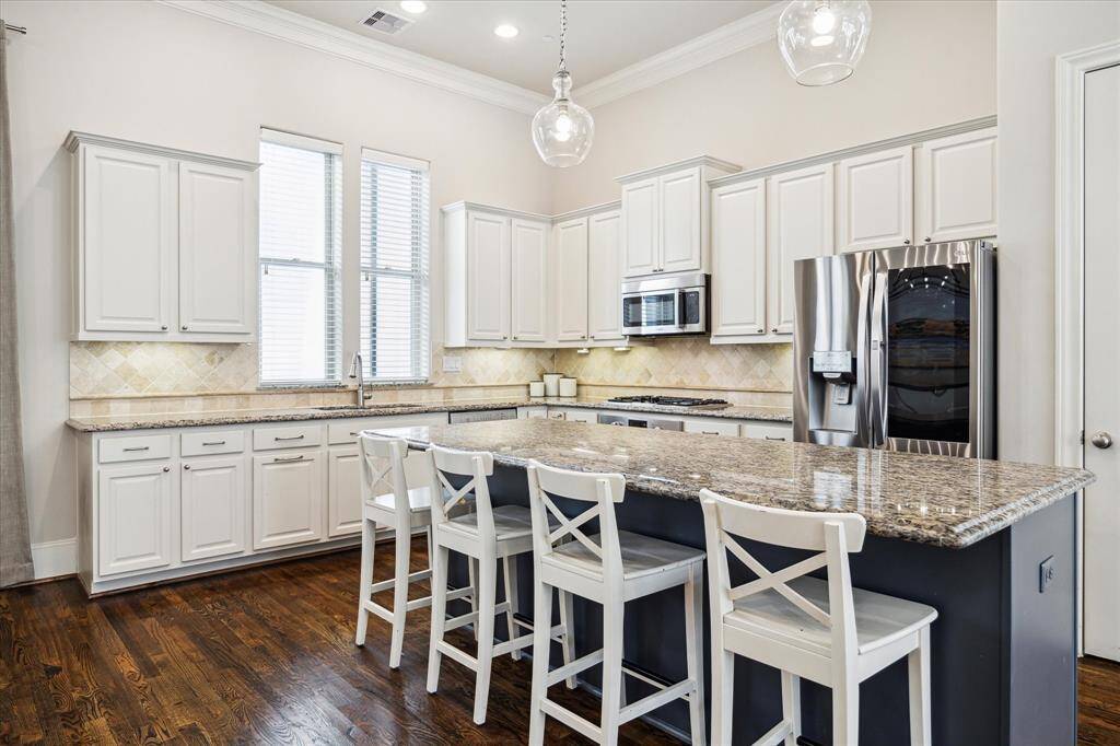 Rows of cabinetry feature granite countertops, tile backsplashes, a trash pull-out and undercabinet lighting.