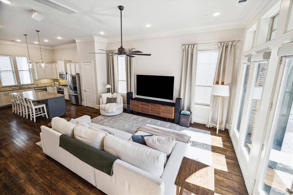 .A wall of south-facing French doors and transom windows drench the living room with natural light, while motorized blinds and an oversized ceiling fan control light and temperature.