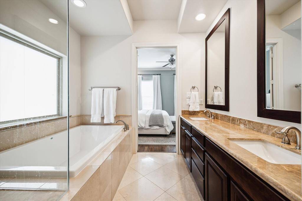 A wide double vanity with granite countertops, two mirrors and brushed nickel fixtures adds plenty of counter space and storage to the primary bathroom.
