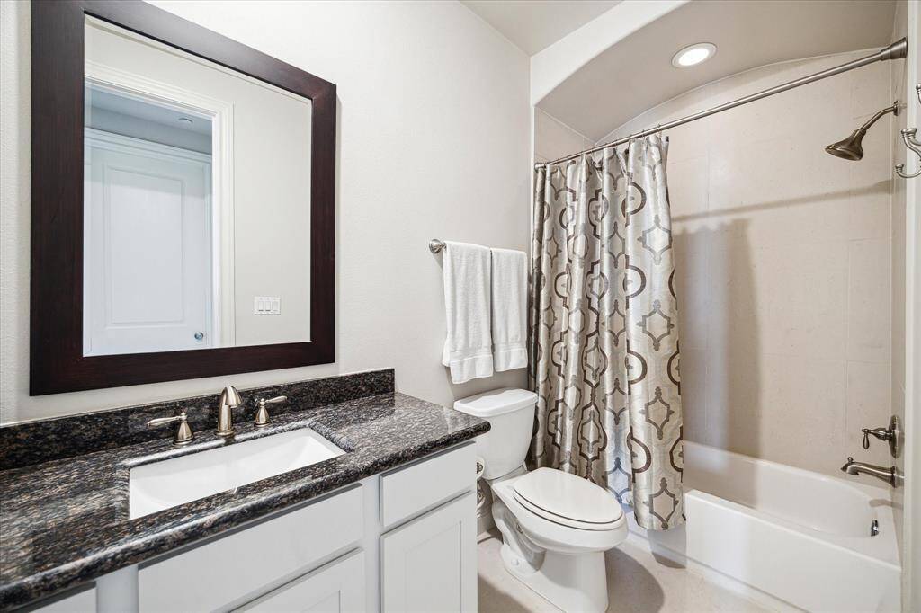 The top-floor bathroom serves the game room and fourth bedroom with a large tub shower and granite vanity.